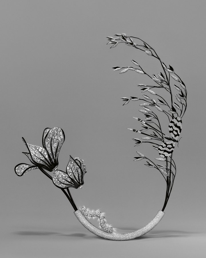 Boucheron, Composition N° 3: Cyclamen, Oat, Caterpillar, Butterfly. Nearly 700 rose-cut diamonds are set in the white gold petals of the cyclamen. The oat stalk is made of black-coated titanium, sculpted into spikelets set with diamonds. The caterpillar is made of white gold set with diamonds and black spinels. Its hairs are imitated by the fibres of a brush and its body is articulated. The butterfly's wings are made of white gold, encrusted with diamonds and enhanced with black lacquer. The white gold vase is set with diamonds.