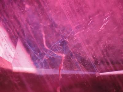 Microscopic view of light reflecting off a fissure filled with lead-glass in a ruby.
